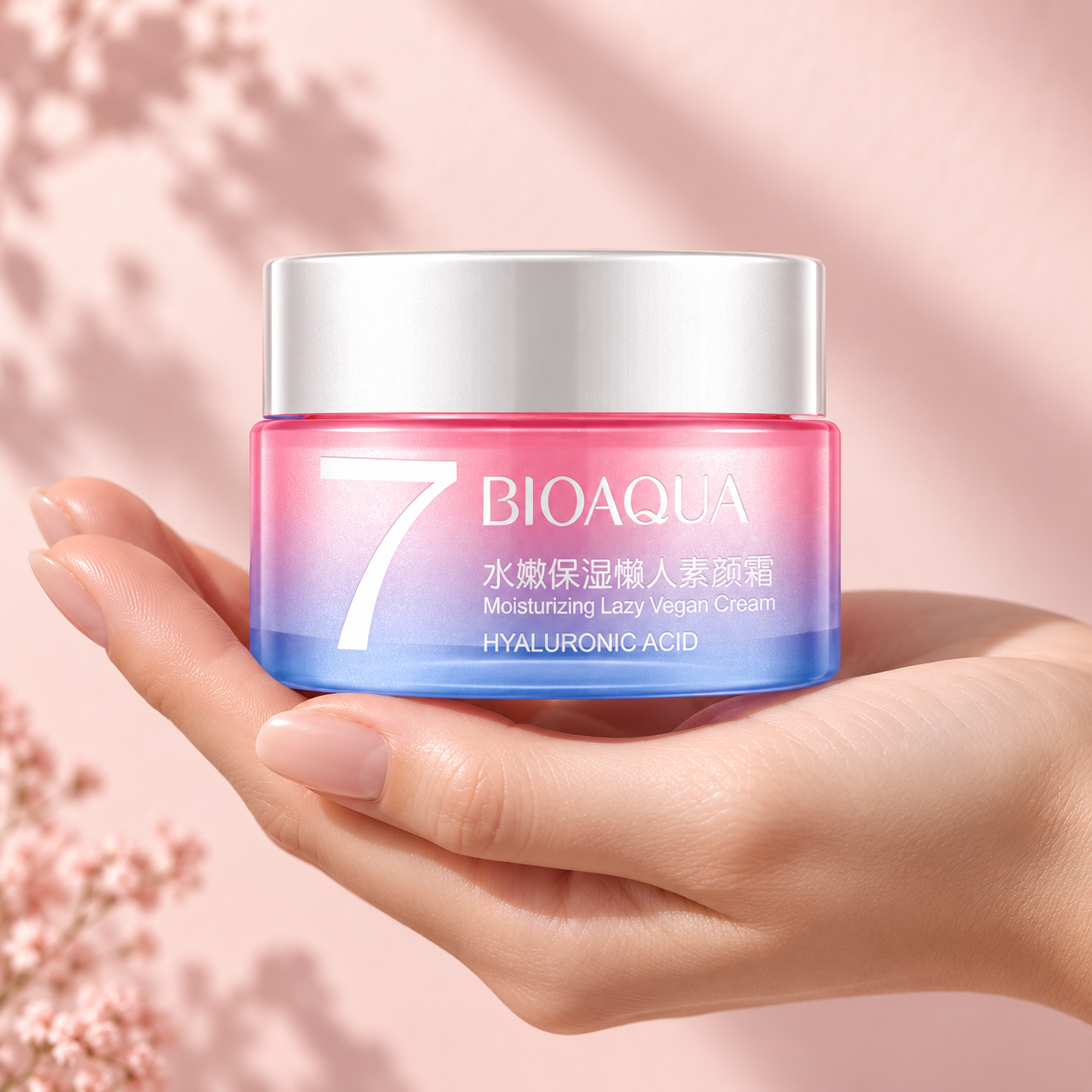 Hand holding BIOAQUA V7 pink and blue cream jar against a blush backdrop